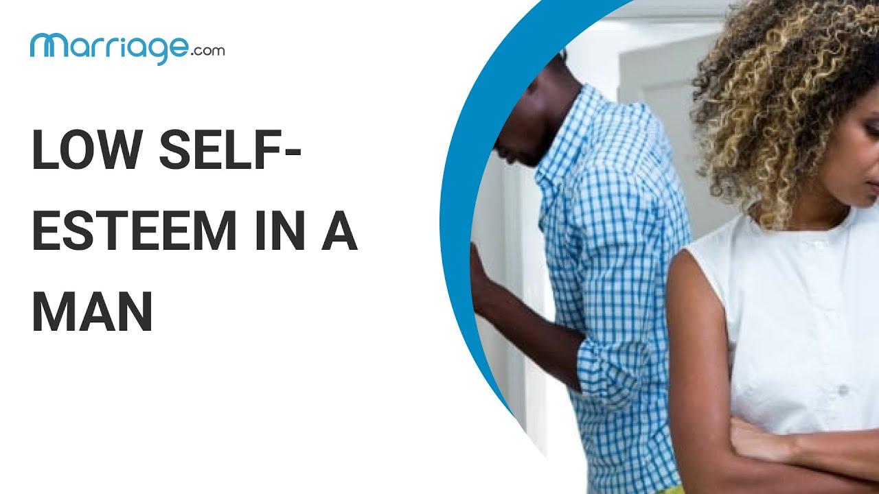 The image features a split design with text on the left and a photograph on the right. The text reads 'LOW SELF-ESTEEM IN A MAN' in bold, black letters. Above the text is the logo 'marriage.com' in a smaller font. The photograph on the right shows a man and a woman. The man is leaning against a wall, appearing contemplative or distressed, while the woman stands with her arms crossed, looking away. The background is a neutral indoor setting. The overall theme suggests a focus on relationship dynamics and mental health.